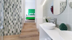 Un baño moderno con un espejo grande, dos lavamanos y una pared de acento verde.