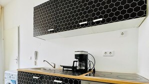 Eine kleine Küche mit schwarzem und weißem, sechseckigem Fliesenrückwand, einer integrierten Waschmaschine und einem Herd.