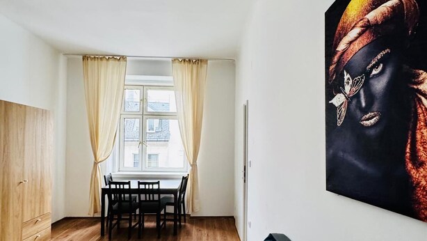Ein modernes Wohnzimmer mit Essbereich, Holzboden, einem großen Fenster mit Vorhängen und einem Wandbild.