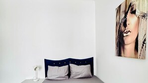 Ein Schlafzimmer mit einem Bett, einem Nachttisch, einer Lampe und einem großen Gemälde an der Wand.