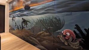 A mural with a ship, sea creatures, and a sunset. - GOHOME (Kaohsiung)