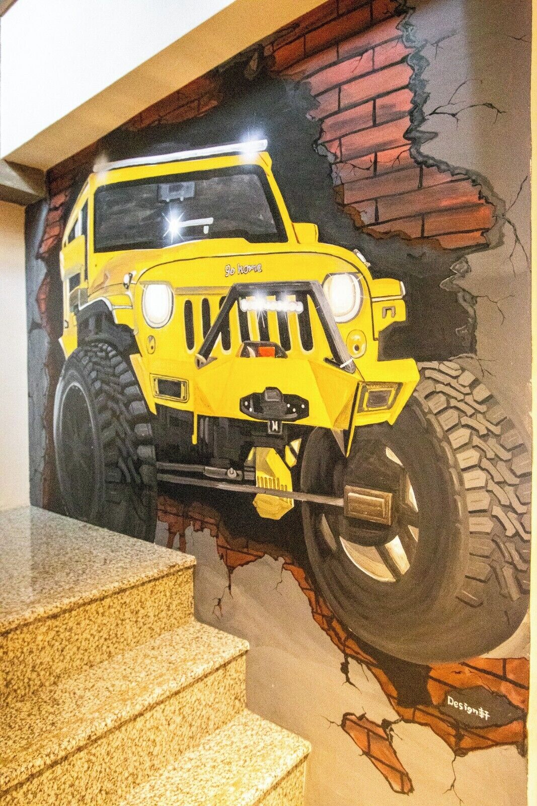 Une fresque représentant un véhicule tout-terrain jaune sur un mur dont le motif imite un mur de briques.