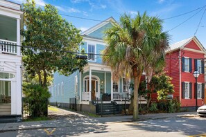 A row of houses with a porch, a palm tree, and a street lamp.