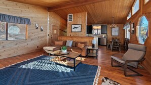 A cozy cabin interior with a wooden interior, a dining area, and a kitchen. - Close to Bear Mountain Ski Resort, Golf Course and Zoo! PET FRIENDLY 🐾! Rock Fireplace! Mountain Views! (Big Bear City)
