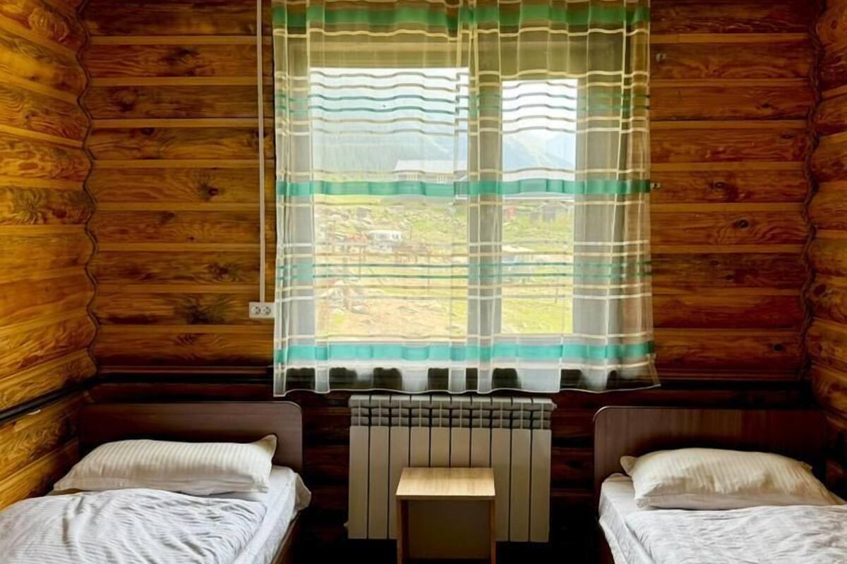 A cabin with two beds, a window with a curtain, and a radiator.