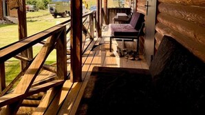 A wooden cabin with a porch, a bench, and a table. - Arashan Hotel (Teploklyuchenka)