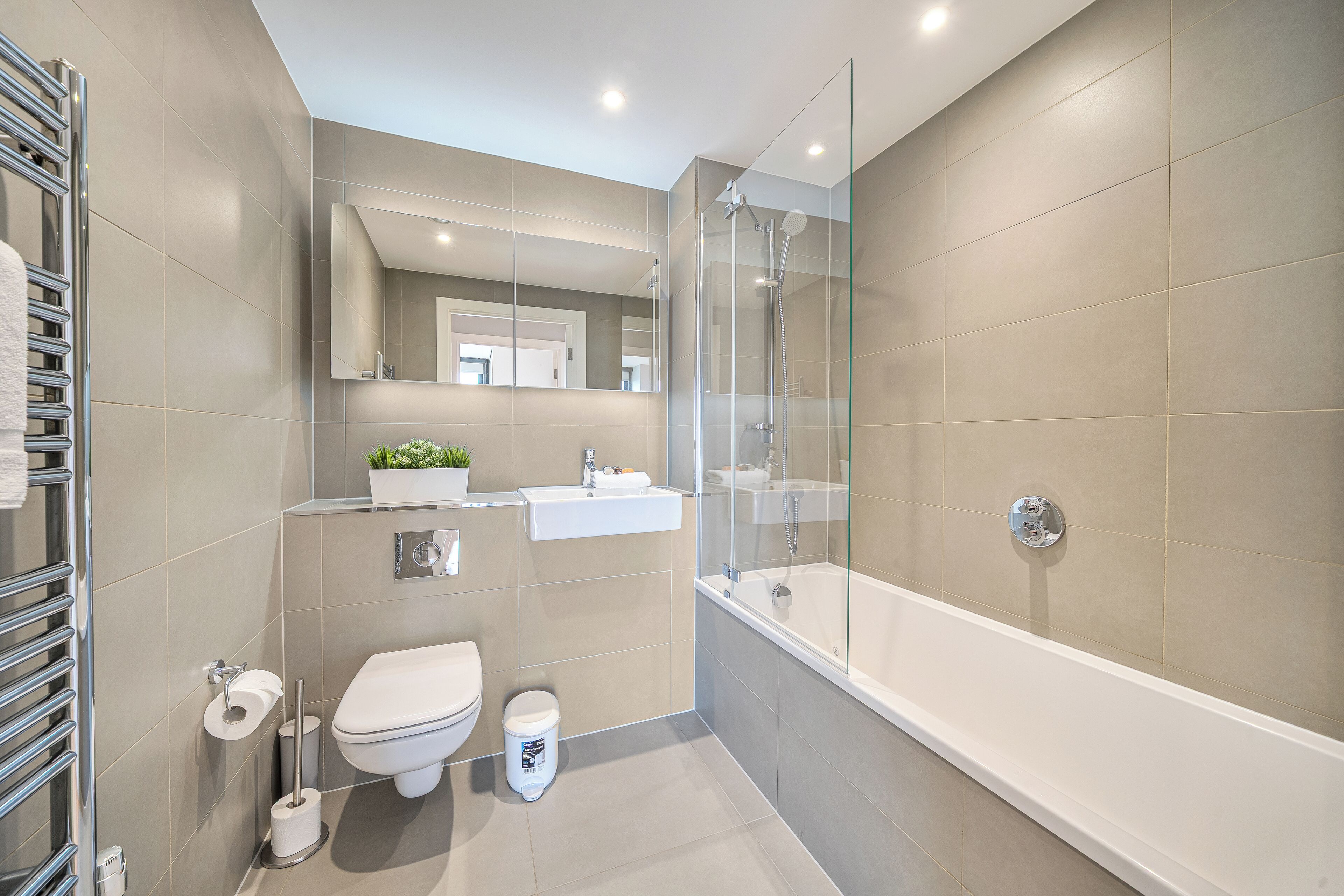 A modern bathroom with a glass-enclosed shower, a white sink, and a toilet.