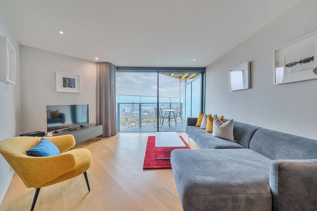 A modern living room with a sofa, armchair, and a flat-screen TV.