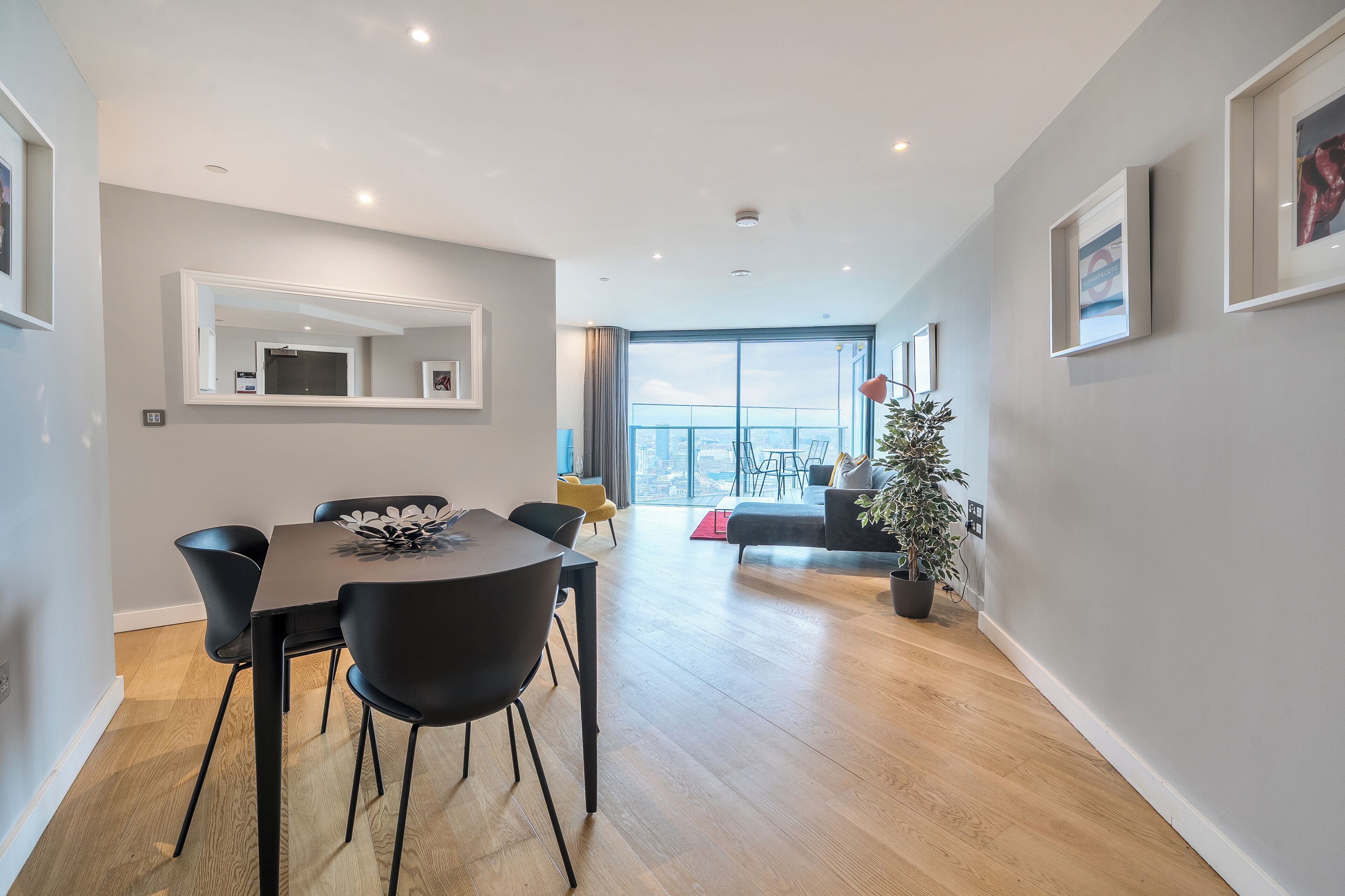 A modern living room with a dining area, large windows, and a view of the city.