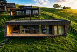 Een modern huis met twee verdiepingen, een plat dak, grote ramen en een terras.