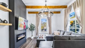 A modern living room with a fireplace, a sofa, a TV, and a large window with curtains. - 6BR Gem in Midtown Atlanta (Atlanta)