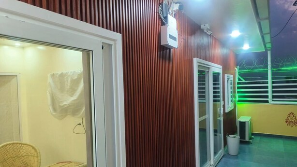 A room with a sliding glass door, a white air conditioning unit, a window with horizontal blinds, and a tiled floor. - The King Residency (New Delhi)