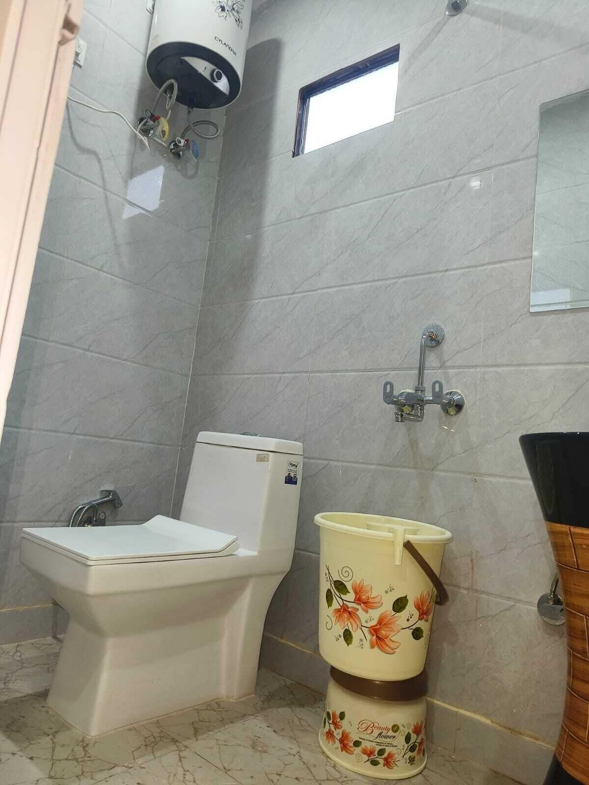 A bathroom with a toilet, bidet, and a small window.