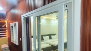A room with a bed, a window, and a door leading to another space. - The King Residency (New Delhi)