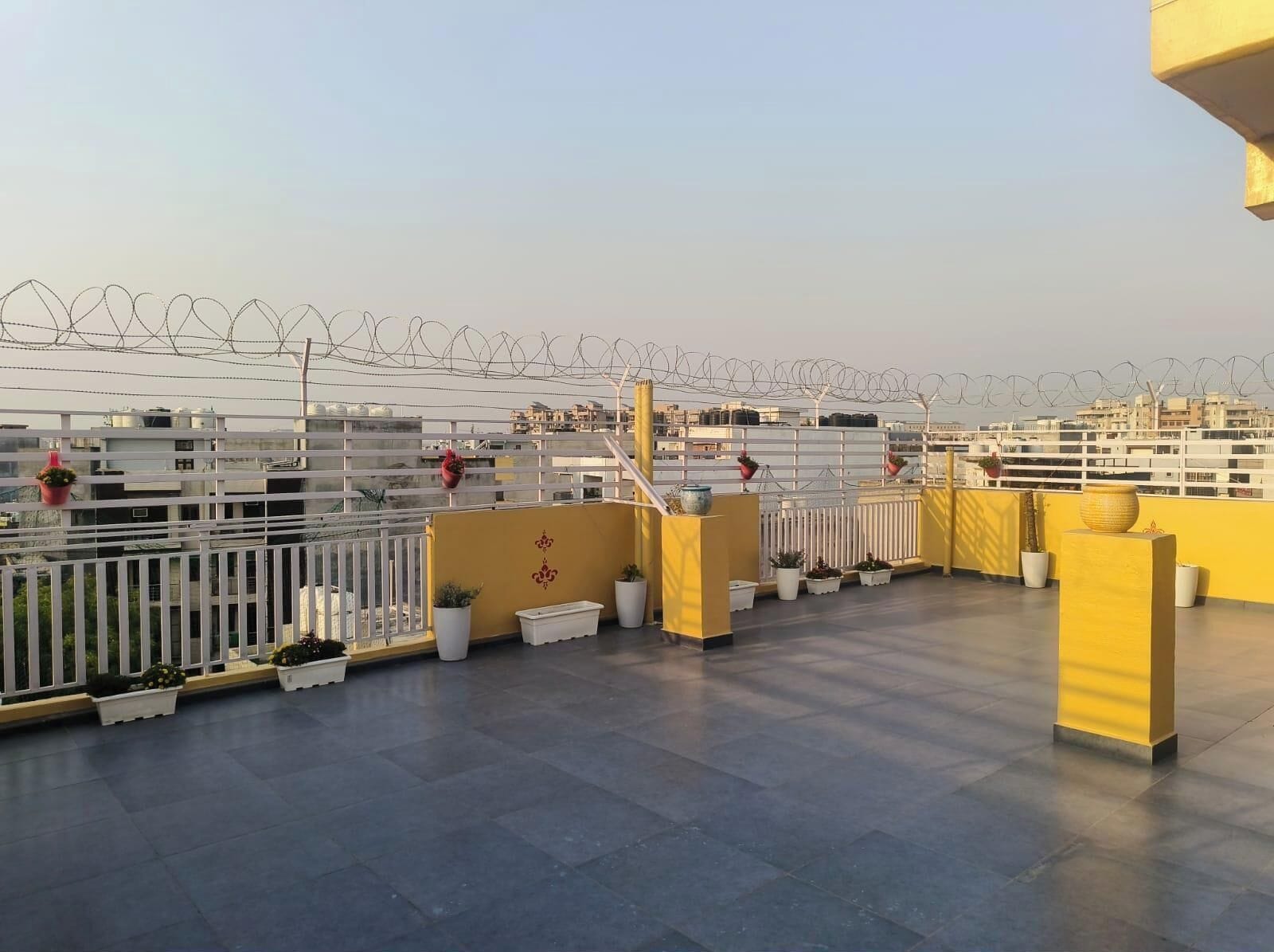 Eine Dachterrasse mit gelander, Topfpflanzen und Blick auf die Stadtlandschaft.