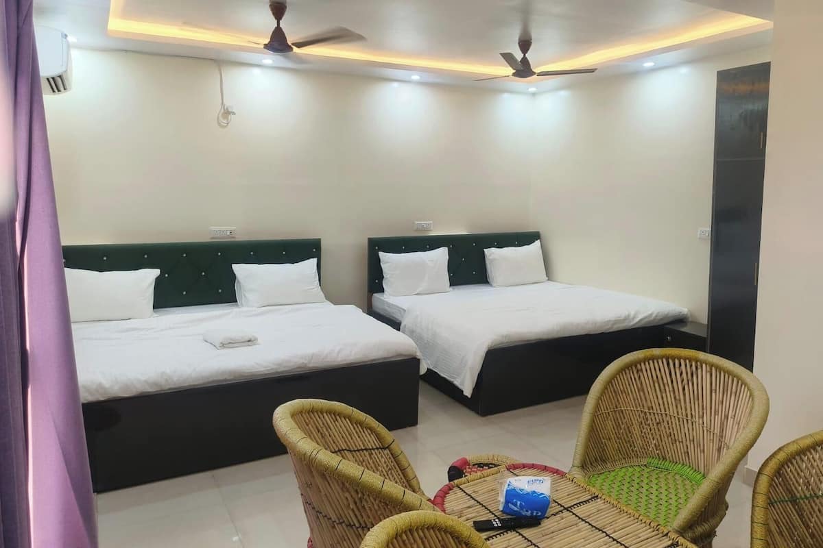 A hotel room with two beds, ceiling fans, a table with chairs, and a wall-mounted air conditioner.