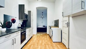 A modern kitchen with white cabinetry, a wooden floor, and a central island. - Lovely 2BR for 5 Peaceful Central Stay (Klosterneuburg)