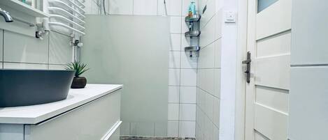 A modern bathroom with a large mirror, a sink, a shower, and a toilet.