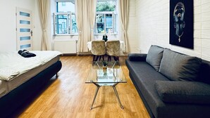 A modern room with a bed, a glass coffee table, a sofa, and a large window with curtains. - Lovely 2BR for 5 Peaceful Central Stay (Klosterneuburg)