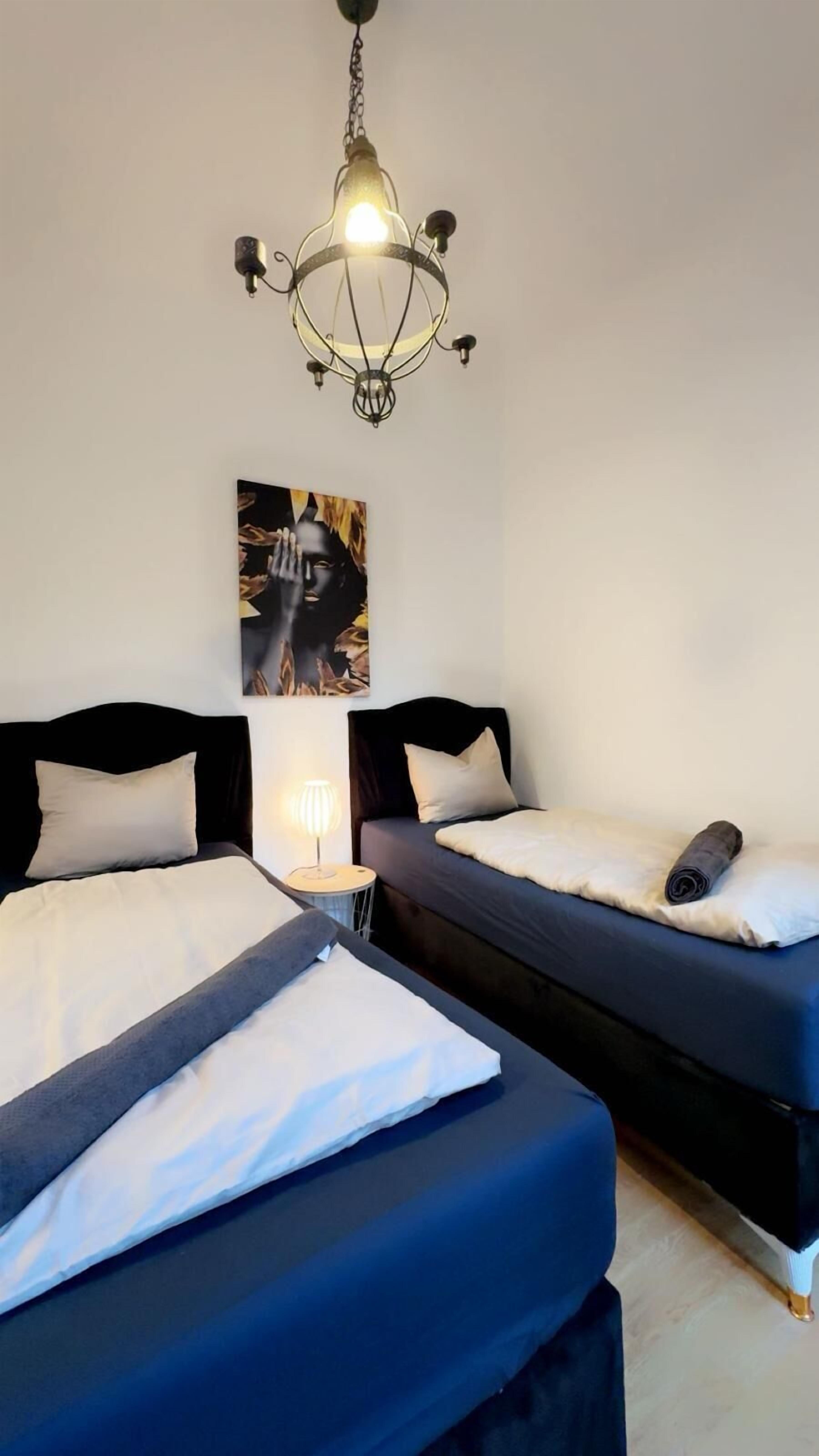 Una stanza con due letti, un lampadario e un quadro appeso al muro.