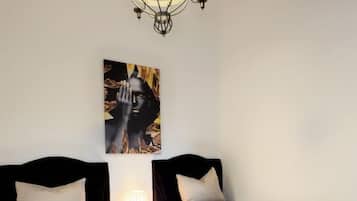 Una stanza con due letti, un lampadario e un quadro appeso al muro.
