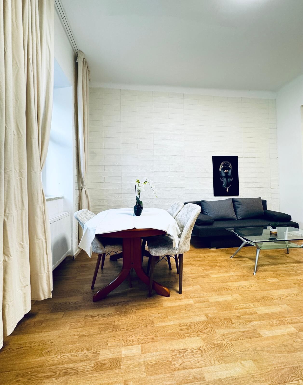 Una sala moderna con una mesa redonda de comedor, un sofá oscuro y una mesa de centro de vidrio.
