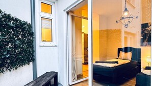 A modern bedroom with a large sliding glass door, a wooden bench, and a small table. - Lovely 2BR for 5 Peaceful Central Stay (Klosterneuburg)