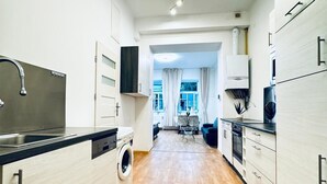 A modern kitchen with a washing machine, a sink, and a dining area with a view. - Lovely 2BR for 5 Peaceful Central Stay (Klosterneuburg)