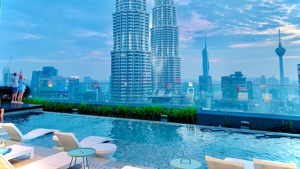 A rooftop pool with lounge chairs and a view of the Petronas Towers. - STAR KLCC By Super Suites  (Kuala Lumpur)