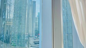 A modern building with a glass facade, viewed through a window with white curtains. - STAR KLCC By Super Suites  (Kuala Lumpur)