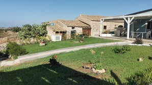 Una casa con techo de tejas, un jardín pequeño y un patio con muebles de exterior.