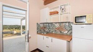Cocina compacta con vistas a través de una puerta de vidrio, un microondas y un armario con un zócalo decorativo.