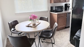 A compact kitchen with a dining table, chairs, a microwave, and a refrigerator.
