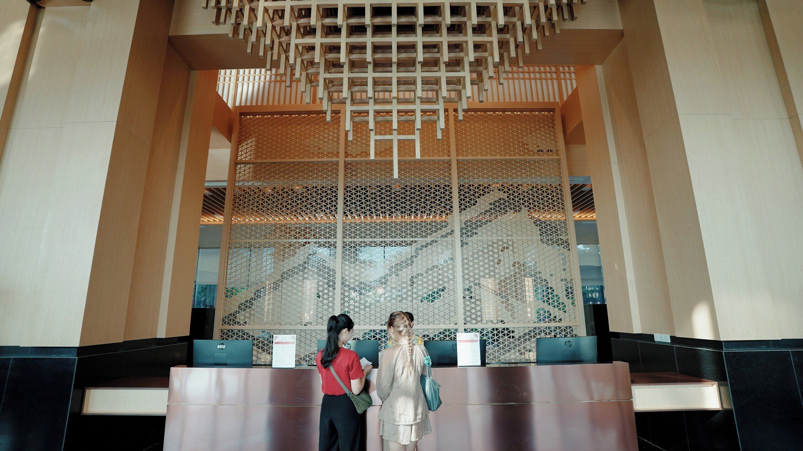 A reception area with a decorative wooden lattice wall, a reception desk, and a seating area with chairs.