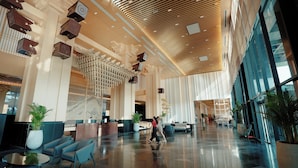 Un hall d’entrée spacieux avec un plafond haut, un mobilier moderne et un grand comptoir de réception.