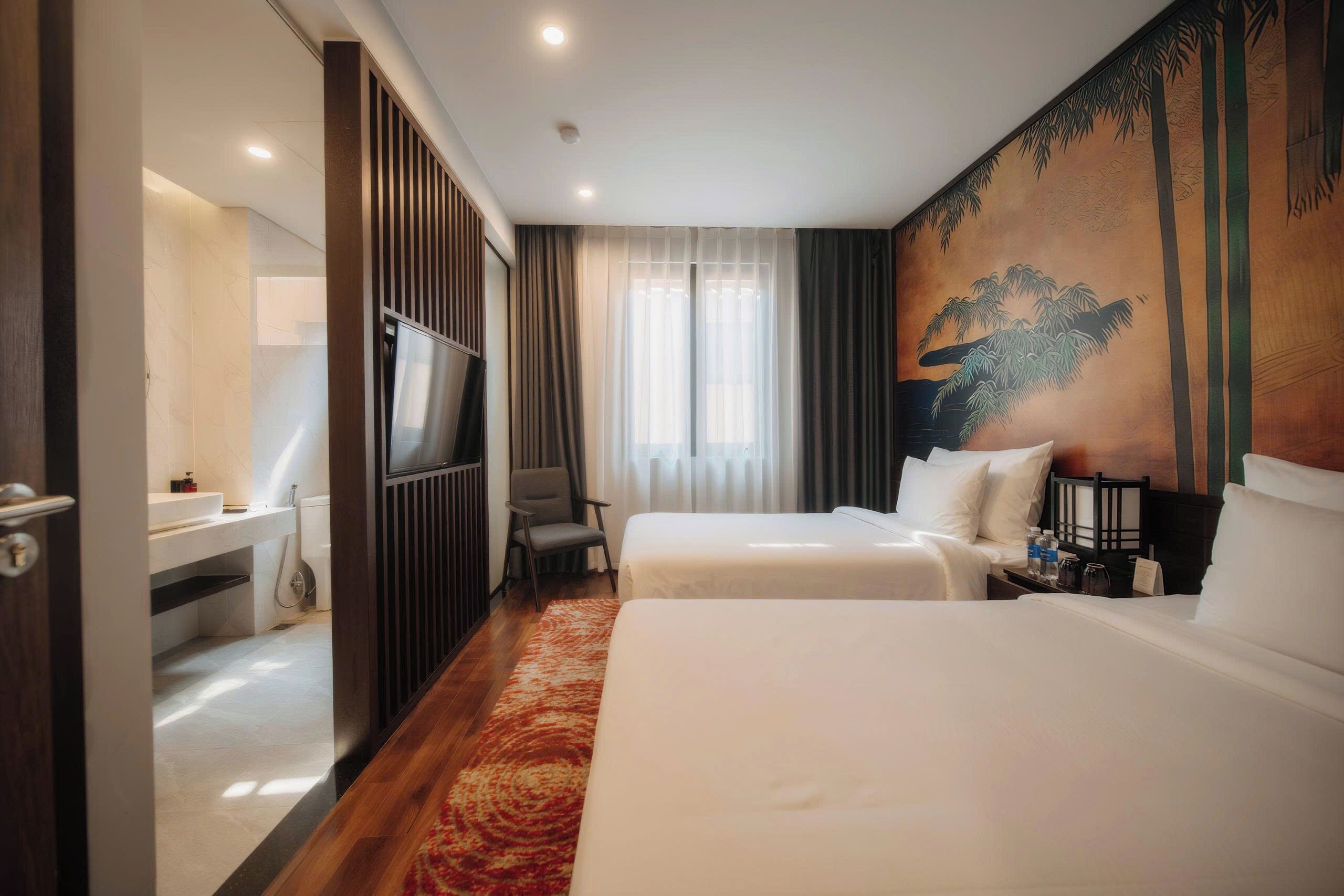 A hotel room with two beds, a TV, a desk, and a painting on the wall.
