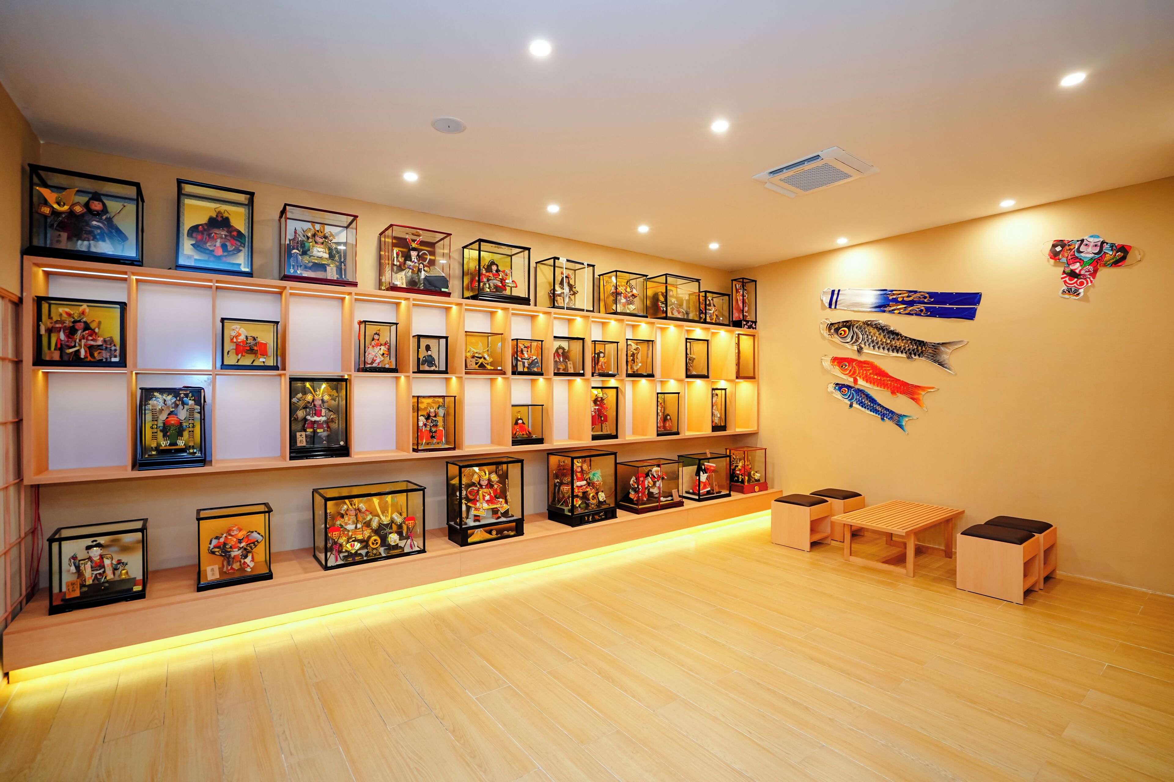 A room with wooden flooring, a wall of framed pictures, and a small wooden table with two chairs.