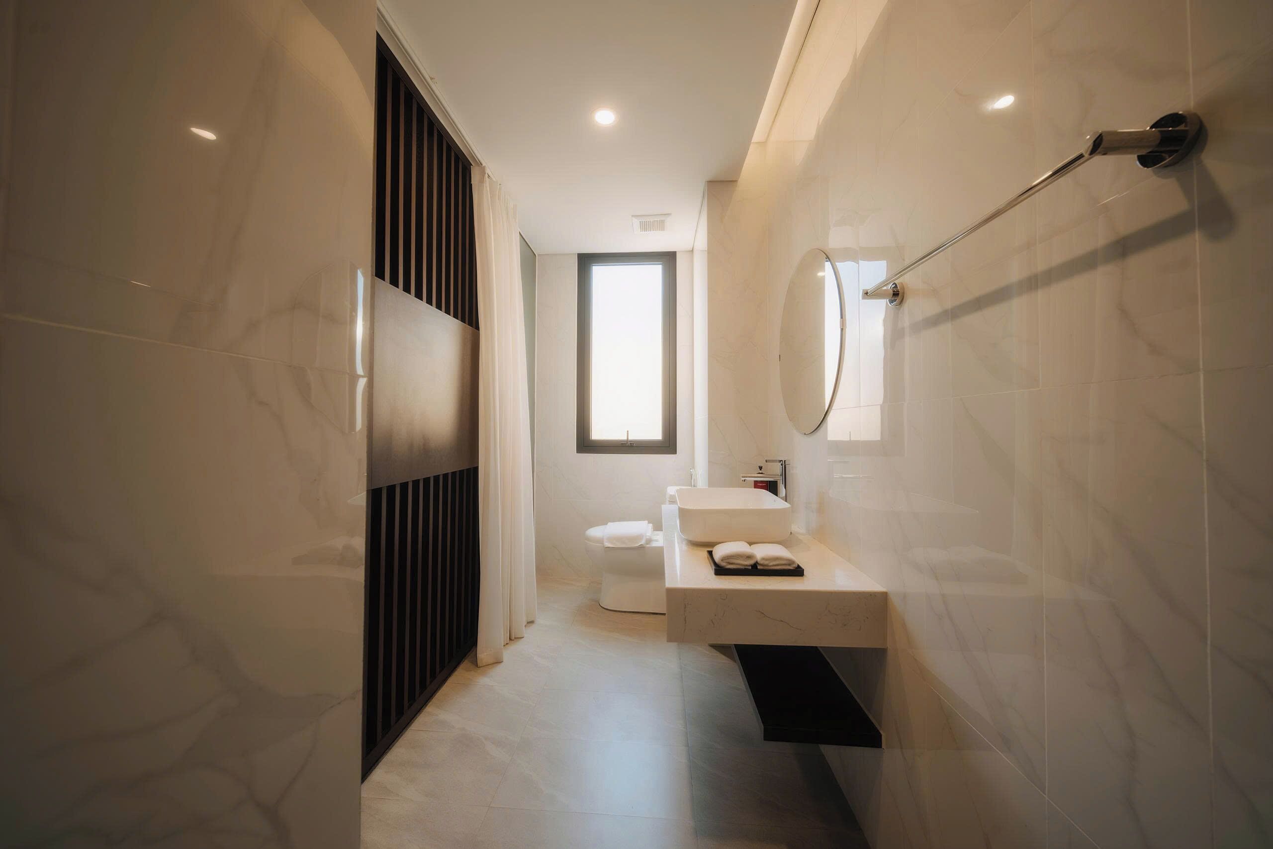 A modern bathroom with a toilet, sink, and mirror.