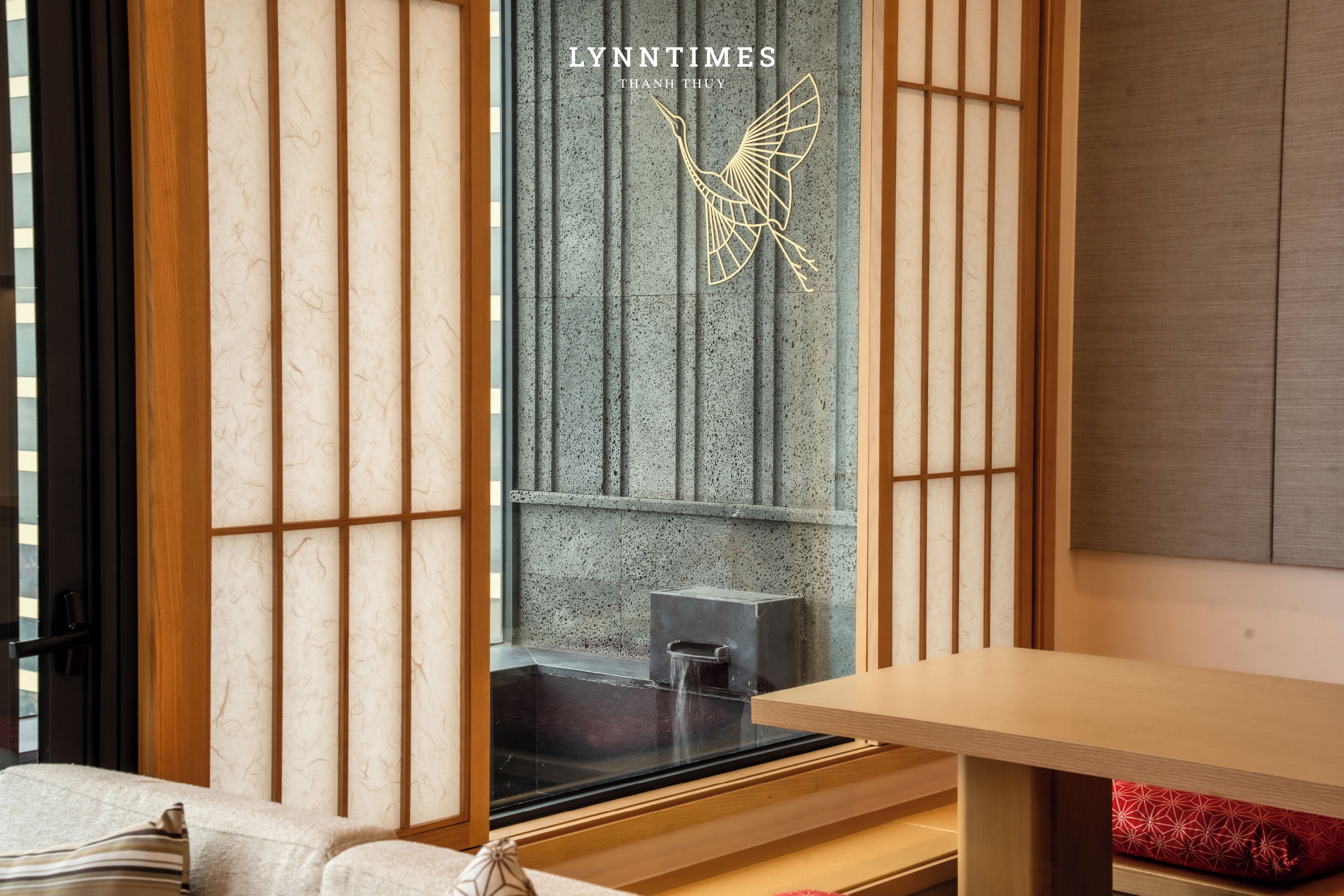 A traditional Japanese room with tatami flooring, a low wooden table, and a sliding door with a decorative gold crane design.