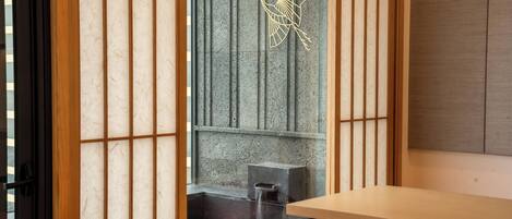 A traditional Japanese room with tatami flooring, a low wooden table, and a sliding door with a decorative gold crane design.