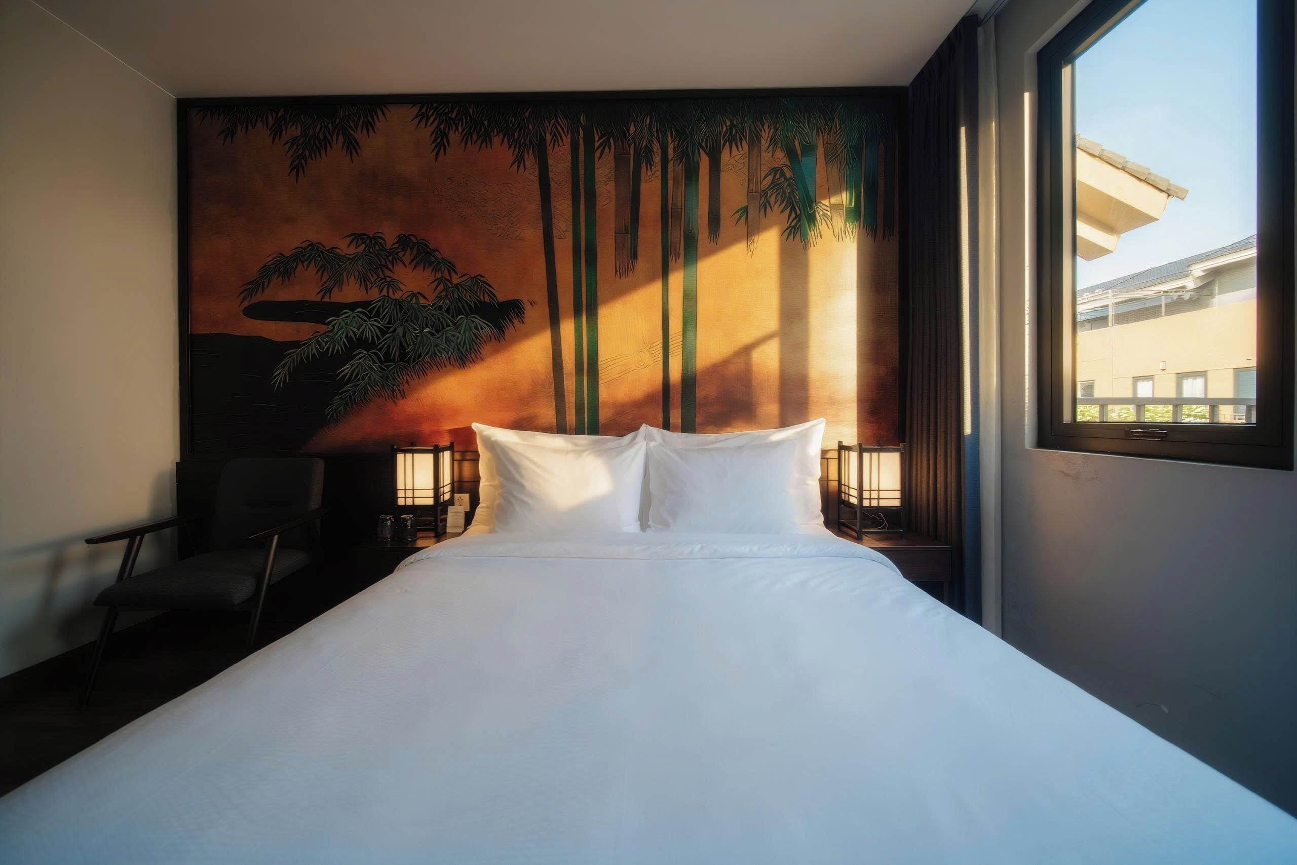 A hotel room with a large bed, a chair, a nightstand, and a wall mural of a forest.