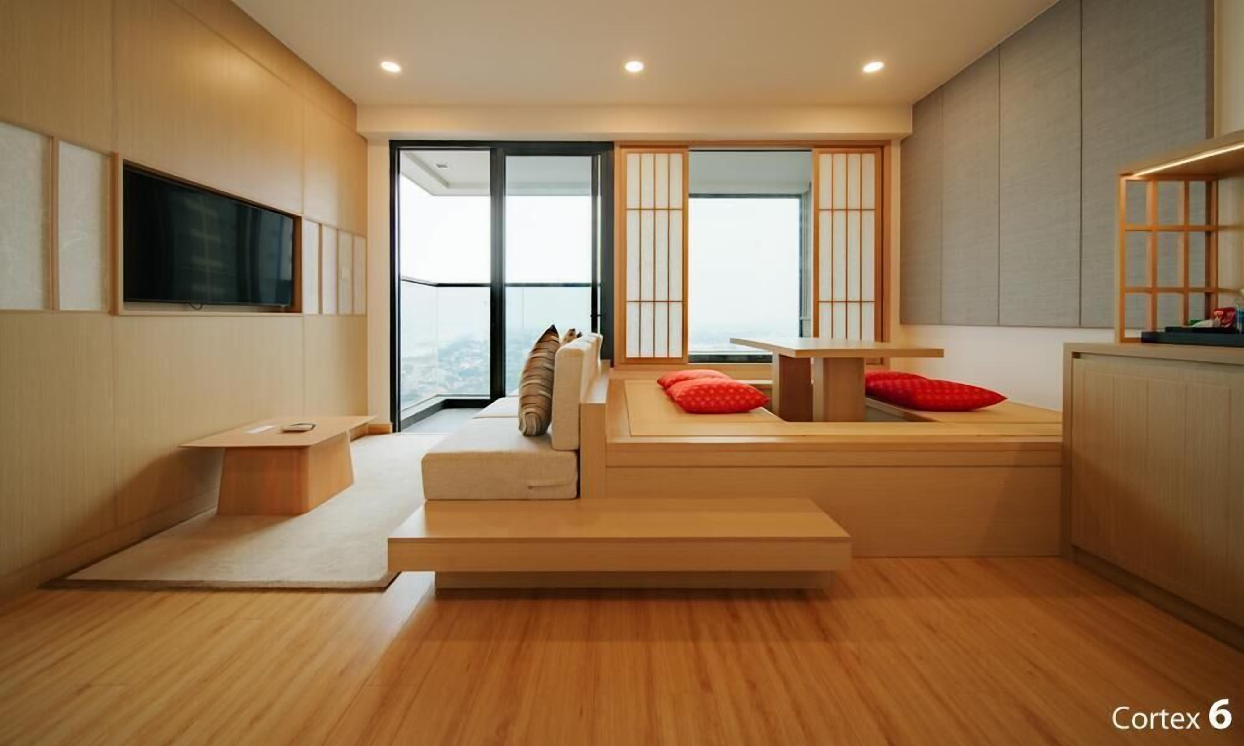 A modern, minimalist room with a built-in bench and a small table, a sliding glass door leading to a balcony, and a large window with a view.