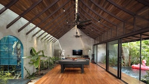 Ein geräumiger Innenbereich mit Billardtisch, Deckenventilator und Fernseher.