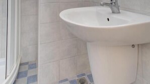 A bathroom with a white sink, a mirror, and a shower area.