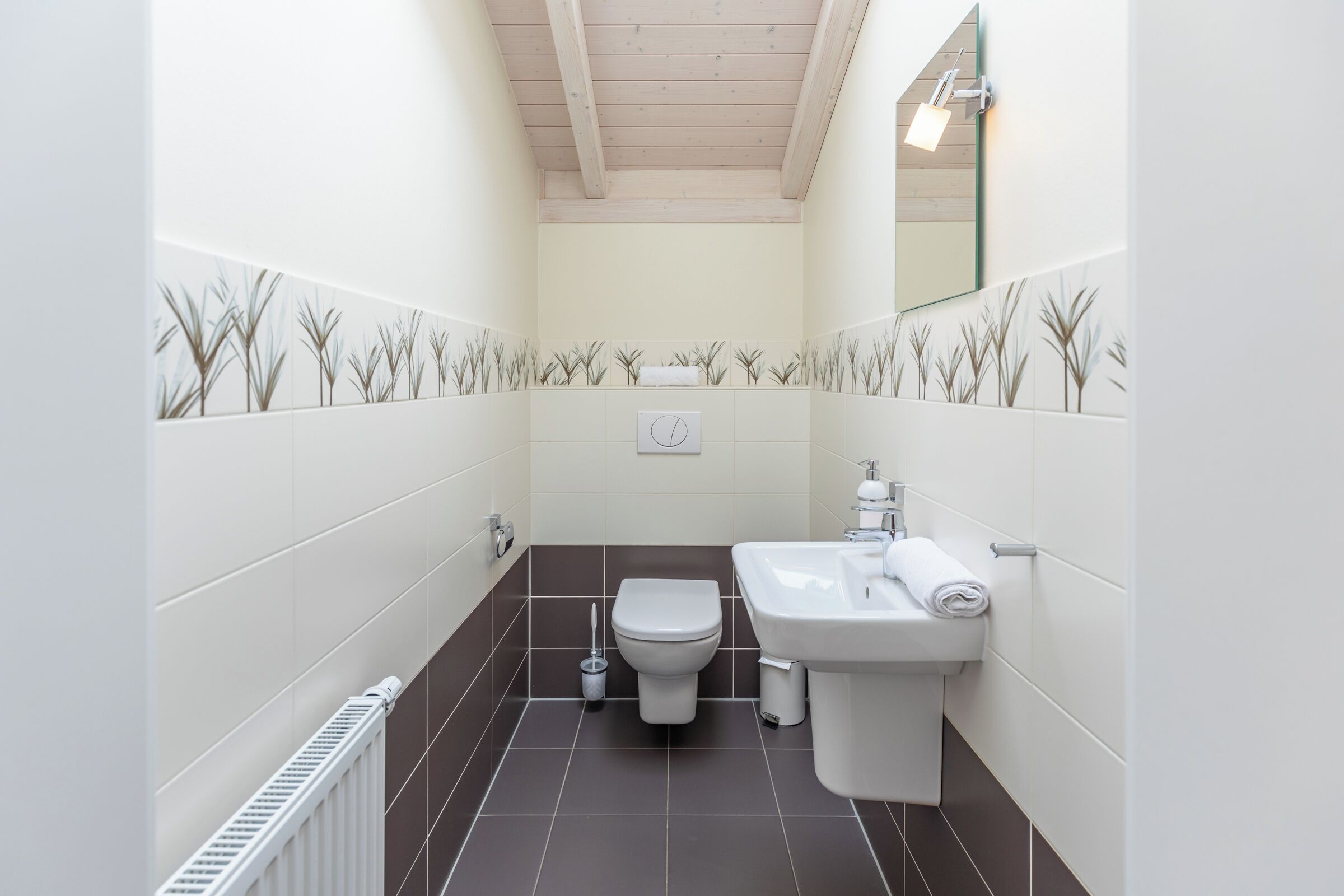 A narrow bathroom with a toilet, sink, and radiator.