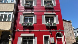 A red building with multiple windows, some with shutters, and balconies with flower boxes. - Balatside Family Suite (İstanbul)