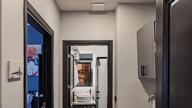 A narrow hallway with a patterned floor, leading to a bathroom with a mirror and sink. - Balatside Family Suite (İstanbul)