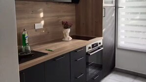 Een moderne keuken met donkere kastjes, een houten aanrechtblad en een ingebouwde oven.