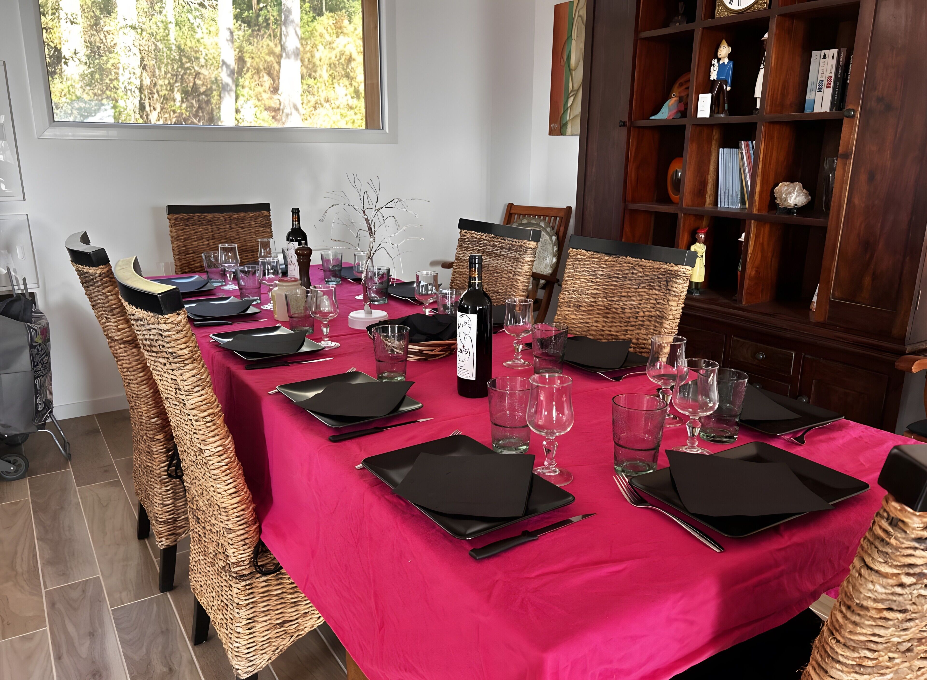 A dining table set with black napkins, wine glasses, and a bottle of wine.