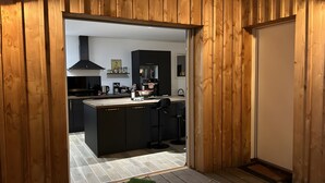 A modern kitchen with dark cabinetry, a central island, and a view into the adjacent living area. - Villa 'Mimosa - Vue Exceptionnelle' with Lake View, Private Terrace and Wi-Fi (Lacanau)
